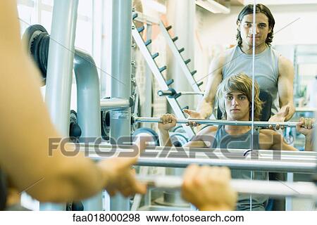 Man lifting barbell while second man spots View Large Photo Image Stock Photo - Man lifting barbell while second man spots. Fotosearch