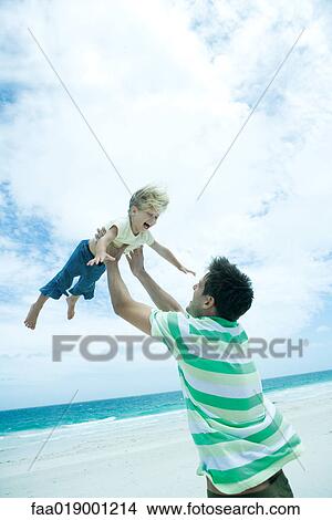Man lifting child into air on beach View Large Photo Image Picture - Man lifting child into air on beach. Fotosearch