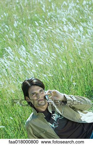 Man lying in grass, using cell phone View Large Photo Image Stock Image - Man lying in grass, using cell phone. Fotosearch