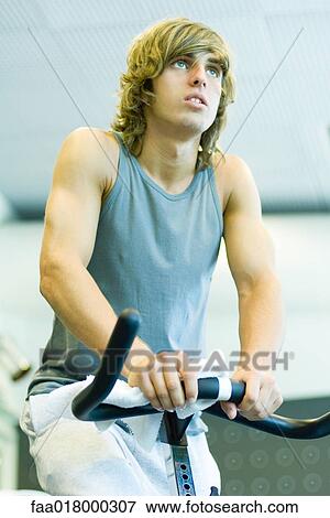 Stock Photo - Man riding exercise bike. Fotosearch