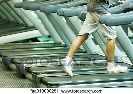 Stock Image - Man running on treadmill, waist down. Fotosearch
