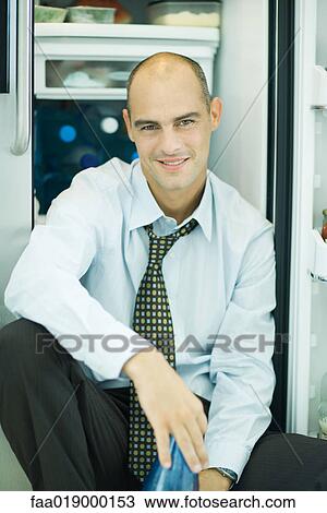 Man sitting in front of open refrigerator, smiling at camera View Large Photo Image Stock Image - Man sitting in front of open refrigerator, smiling at camera. Fotosearch