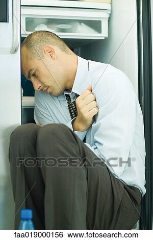 Man sitting in front of open refrigerator in fetal position View Large Photo Image Stock Photograph - Man sitting in front of open refrigerator in fetal position. Fotosearch