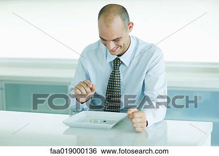 Stock Photograph - Man sitting in front of plate containing vitamins. Fotosearch