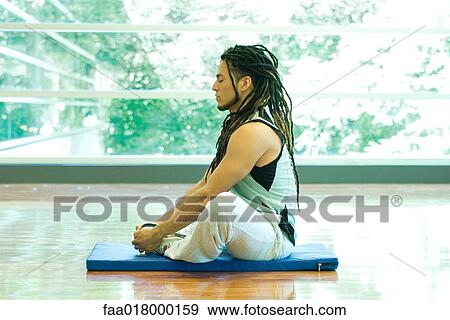 Stock Photo - Man sitting in lotus position, side view. Fotosearch