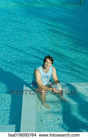 Man sitting in pool, reading, looking up at camera View Large Photo Image Picture - Man sitting in pool, reading, looking up at camera. Fotosearch