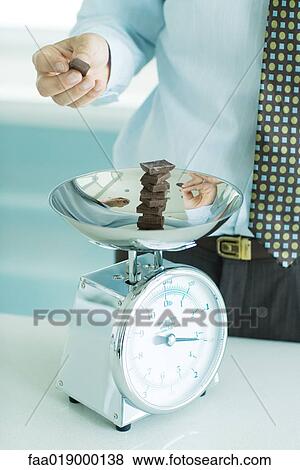 Man stacking chunks of chocolate on kitchen scale View Large Photo Image Stock Photo - Man stacking chunks of chocolate on kitchen scale. Fotosearch