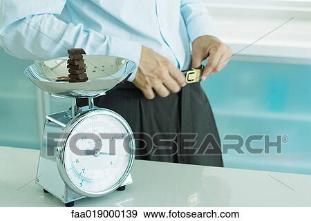 Man standing by scale containing chunks of chocolate on kitchen scale View Large Photo Image Stock Photo - Man standing by scale containing chunks of chocolate on kitchen scale. Fotosearch