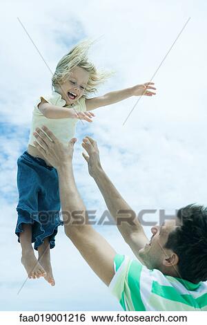 Stock Photograph - Man throwing child into air. Fotosearch