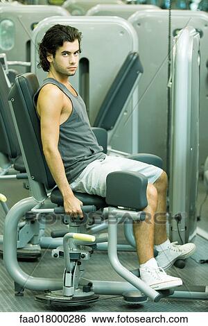 Stock Photograph - Man working out on weight machine. Fotosearch