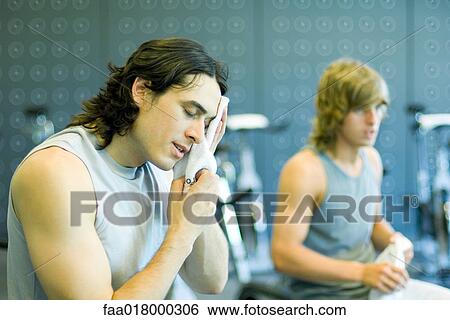 Men in workout room, one wiping face View Large Photo Image Stock Photograph - Men in workout room, one wiping face. Fotosearch
