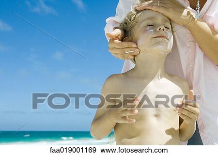 Mother putting sunscreen on child at beach View Large Photo Image Stock Photo - Mother putting sunscreen on child at beach. Fotosearch