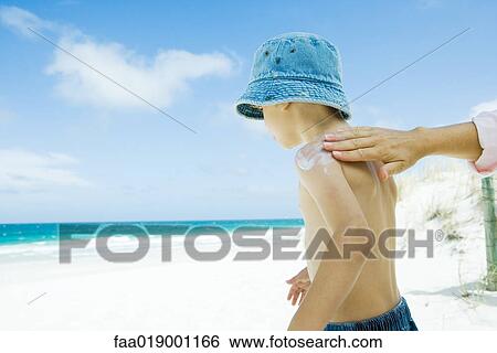Mother putting sunscreen on child at beach View Large Photo Image Stock Photograph - Mother putting sunscreen on child at beach. Fotosearch