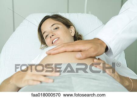 Pregnant woman lying on back, doctor's hand on stomach View Large Photo Image Stock Image - Pregnant woman lying on back, doctor's hand on stomach. Fotosearch