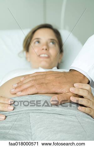 Pregnant woman lying on back, doctor's hand on stomach View Large Photo Image Stock Image - Pregnant woman lying on back, doctor's hand on stomach. Fotosearch