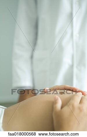 Pregnant woman lying on back, hands on stomach, doctor in background View Large Photo Image Stock Photo - Pregnant woman lying on back, hands on stomach, doctor in background. Fotosearch