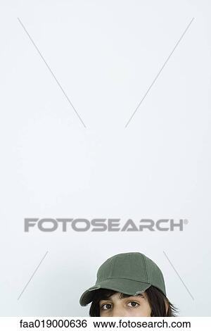 Stock Photograph - Teen boy wearing cap, looking at camera, partial view. Fotosearch