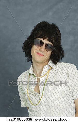 Stock Photo - Teen boy wearing sunglasses and necklace, smiling at camera, portrait. Fotosearch