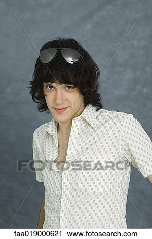 Stock Image - Teen boy wearing sunglasses on top of head, smiling at camera, portrait. Fotosearch