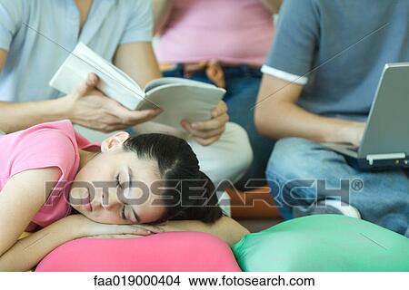 Picture - Teen friends hanging out together, focus on girl sleeping in foreground. Fotosearch