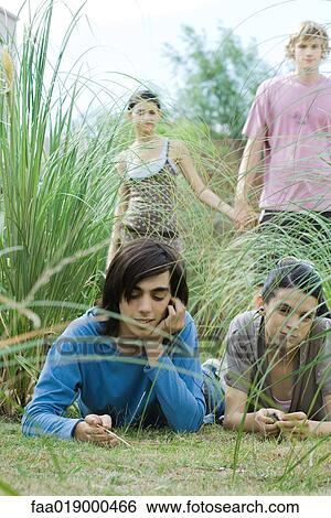 Stock Photograph - Teen friends lying in grass. Fotosearch