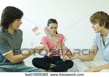 Teen friends playing cards, one throwing cards into the air View Large Photo Image Stock Image - Teen friends playing cards, one throwing cards into the air. Fotosearch