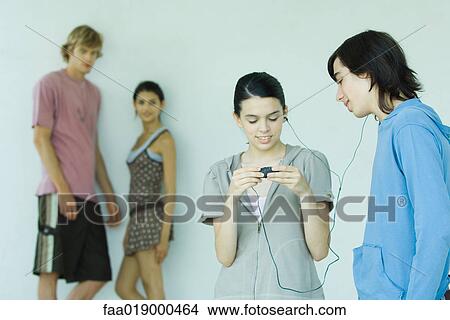 Picture - Teen friends sharing MP3 player. Fotosearch