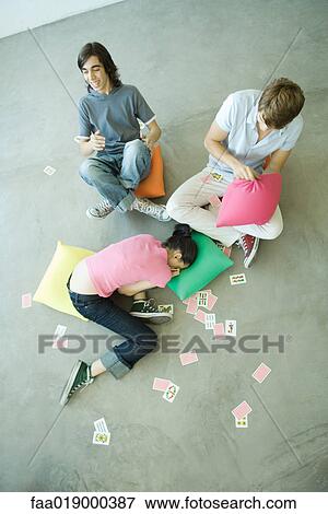 Teen friends with playing cards scattered around them, high angle view View Large Photo Image Stock Photo - Teen friends with playing cards scattered around them, high angle view. Fotosearch
