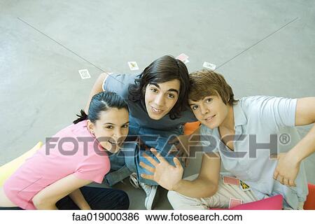 Teen friends with playing cards scattered around them, smiling at camera View Large Photo Image Stock Photograph - Teen friends with playing cards scattered around them, smiling at camera. Fotosearch