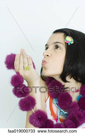 Stock Image - Teen girl holding up fur scarf, blowing kiss, portrait. Fotosearch