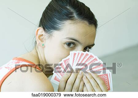 Stock Photo - Teen girl looking over hand of cards. Fotosearch