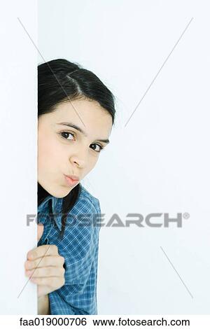 Stock Photograph - Teen girl peeking around wall, puckering at camera. Fotosearch