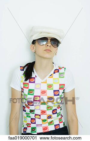 Stock Image - Teen girl wearing cap and sunglasses, portrait. Fotosearch