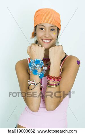 Teen girl wearing lots of accessories, holding up forearms, smiling at camera, portrait View Large Photo Image Stock Image - Teen girl wearing lots of accessories, holding up forearms, smiling at camera, portrait. Fotosearch