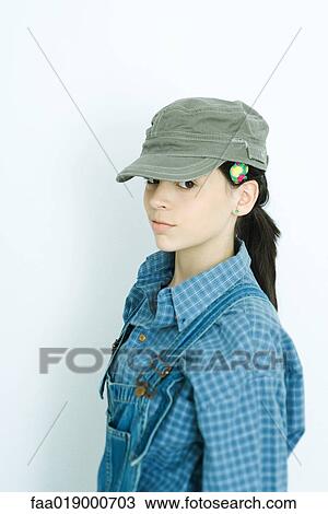 Teen girl wearing overalls and cap, portrait View Large Photo Image Stock Image - Teen girl wearing overalls and cap, portrait. Fotosearch