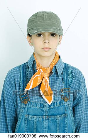 Stock Photo - Teen girl wearing overalls and cap, portrait. Fotosearch