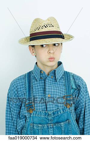 Teen girl wearing overalls and straw hat, making face View Large Photo Image Picture - Teen girl wearing overalls and straw hat, making face. Fotosearch