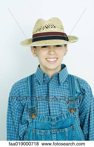 Stock Photo - Teen girl wearing overalls and straw hat, portrait. Fotosearch