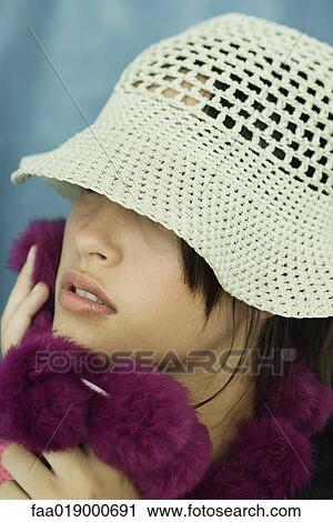 Stock Image - Teen girl wearing sun hat, holding up fur scarf to cheek, close-up, portrait. Fotosearch