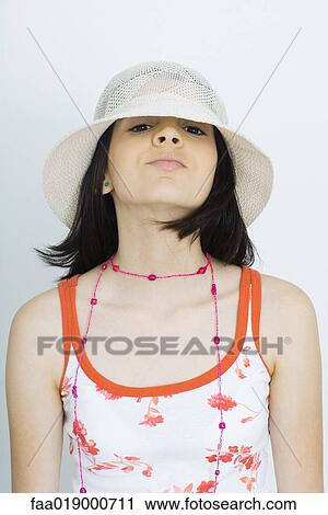 Stock Image - Teen girl wearing sun hat, peeking at camera, portrait. Fotosearch