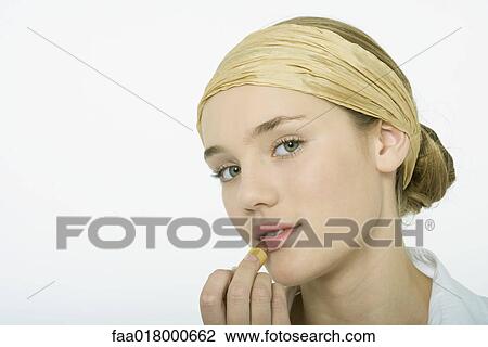 Stock Image - Teenage girl applying lipstick. Fotosearch
