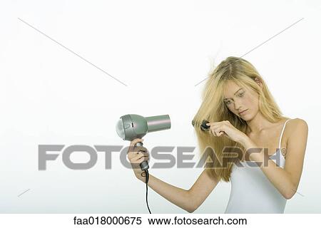 Stock Photography - Teenage girl blow-drying hair. Fotosearch