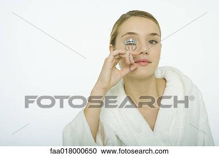 Stock Image - Teenage girl curling eyelashes. Fotosearch