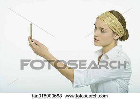 Teenage girl looking at face in hand mirror View Large Photo Image Stock Photo - Teenage girl looking at face in hand mirror. Fotosearch