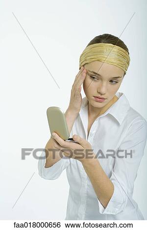 Teenage girl looking at face in hand mirror View Large Photo Image Stock Photograph - Teenage girl looking at face in hand mirror. Fotosearch