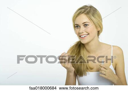 Picture - Teenage girl putting on lipgloss. Fotosearch
