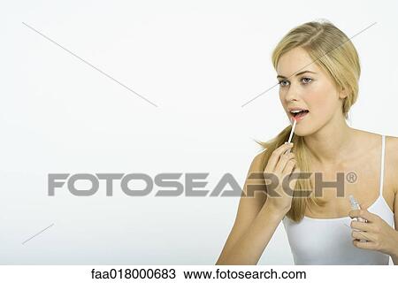 Stock Image - Teenage girl putting on lipgloss. Fotosearch