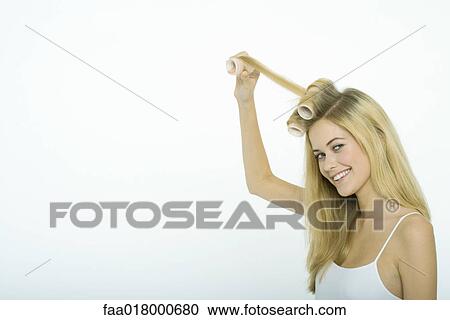 Stock Image - Teenage girl putting rollers in hair. Fotosearch