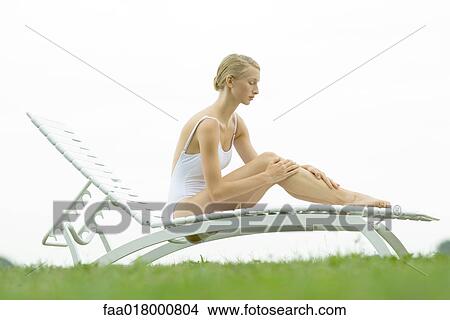 Teenage girl sitting on lounge chair, hands on legs View Large Photo Image Picture - Teenage girl sitting on lounge chair, hands on legs. Fotosearch