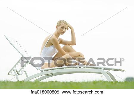 Teenage girl sitting on lounge chair, knee up, looking at camera View Large Photo Image Stock Photography - Teenage girl sitting on lounge chair, knee up, looking at camera. Fotosearch